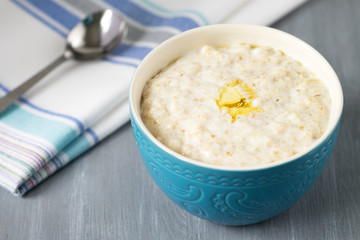 Oatmeal with a Pat of butter in a blue bowl on the table	