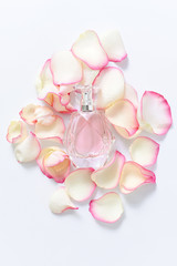 Perfume bottle with flower petals on light background. Perfumery, fragrance collection. Women accessories.