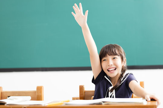 happy little girl  raised hands in classroom.