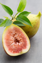 Whole figs and one fig sliced in half on top of a gray table.