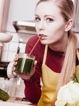 Woman in kitchen holding vegetable juice