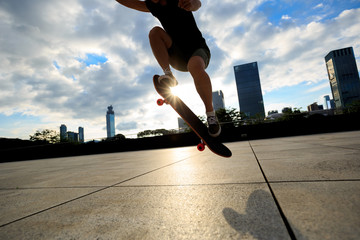 Fototapeta na wymiar young woman skateboarder skateboarding at city
