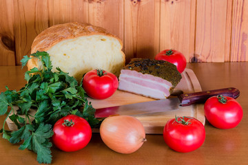 Ham, tomatoes and onion near bread on wooden cutting board. Selective focus