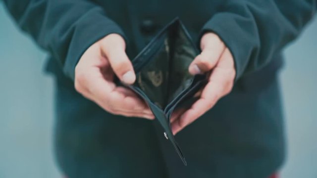 Man turns an empty wallet in his hand close up