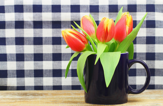 Fototapeta Colorful tulips in navy blue mug with checkered background and copy space  
