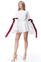 Sexy pretty fashion model blond hair woman wear short white dress with red bow style for party office clothes organic natural silk cotton white background makeup lady skin care body.