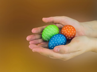 Easter eggs green blue and orange decorated with ornaments lie on the palm of the hand