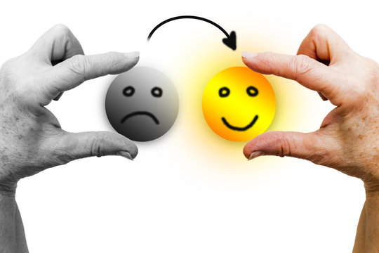 The left hand of a woman in black and white holds a sad icon face. The right hand, in color, holds a happy smiling icon face, shining like the sun. An arrow goes from the sad icon to the happy one