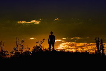 Silhouette of a man at sunset on a background of a colorful beautiful sky with clouds