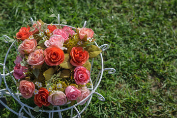 Artificial roses in a basket with grass green background