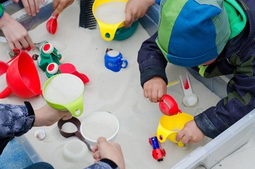 Closeup portrait of playing children´s hands with toys in a sandpit.