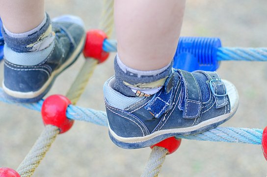 Legs of climbing toddler. Kind of shoes for children various activities.