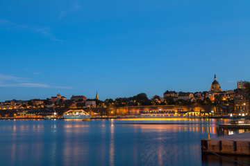 Fototapeta na wymiar Stockholm night vew. Illuminated boats along city embankment.