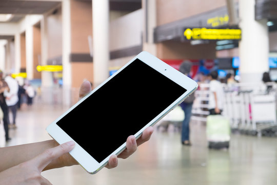 Hands woman are holding touch screen smart phone,tablet on Blurred Traveler at airport terminal for background.