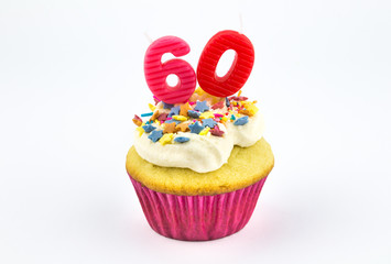Cupcake with number sixty - 60 - pink candles with white vanilla frosting and colour star sprinkles in pink paper case isolated on white background - female birthday background