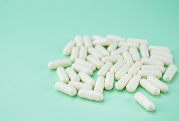 Fototapeta na wymiar White hard capsules isolated on green - medical background