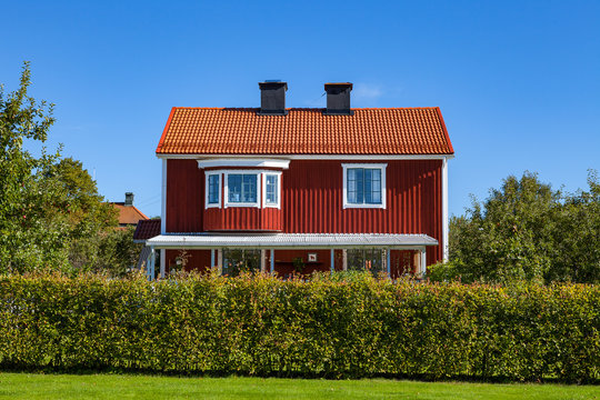 Red Swedish typical house with bushes in small town Hedemora