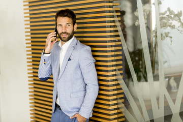 Handsome young businessman using phone in office