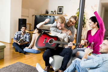 Young people playing guitar and  having a party in the house