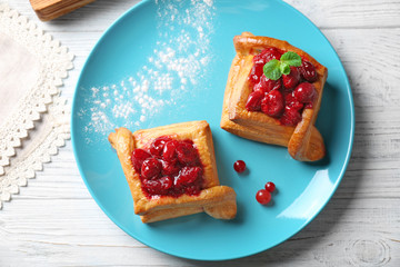 Blue plate with pastries and cherry on white table, top view