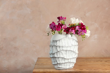 Vase with beautiful freesia flowers on table