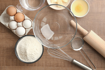 Fototapeta na wymiar Bowl with flour and ingredients for dough on table
