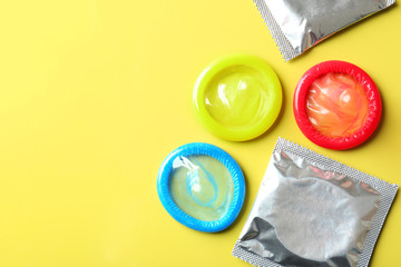 Open and wrapped condoms on color background. Safe sex concept - obrazy, fototapety, plakaty