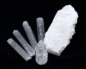 White mexican fish tail selenite with natural selenite rods on black background