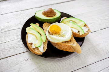 Tasty sandwiches with avocado and egg on plate on white wooden table. Delicious breakfast. Flat lay/ Top view