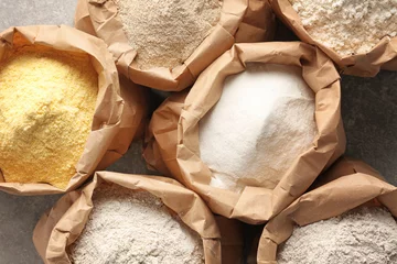  Paper bags with different types of flour on gray background, closeup © Africa Studio