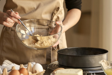 Woman preparing dough for cheese cake in kitchen