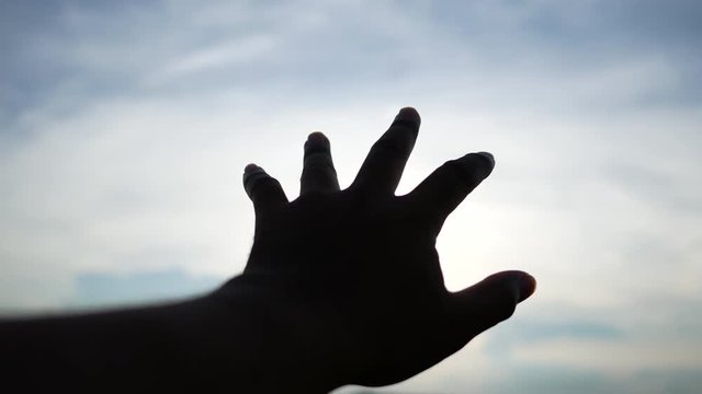 Silhouette of human hand reaching the sun. 