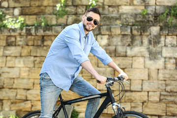 Fototapeta na wymiar Handsome young man riding bicycle outdoors on sunny day