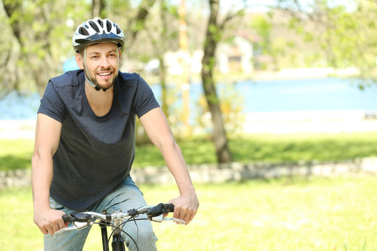 Handsome young man riding bicycle outdoors on sunny day