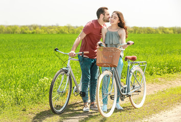 Happy young couple with bicycles in countryside