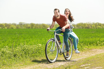 Naklejka na ściany i meble Happy young couple riding bicycle in countryside
