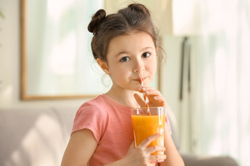 Cute little girl drinking juice at home