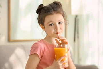 Wall murals Juice Cute little girl drinking juice at home