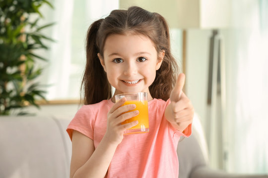 Cute little girl with glass of juice at home