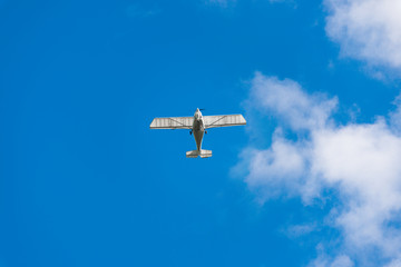 Airplane in the sky. Small passenger plane flying in the blue sky. White aircraft against the blue cloudy sky.  Airplane flying among clouds.White small passenger aircraft. 
