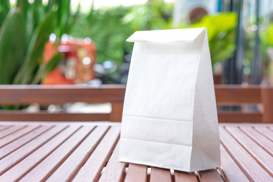 Blank white paper bag for taking away food on a wooden table