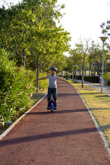 El niño con el casco esta paseando en el parque con la rueda Monowheel..  scooter electrico