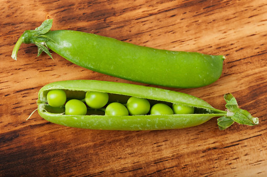 Sweet green peas on an old wooden background.