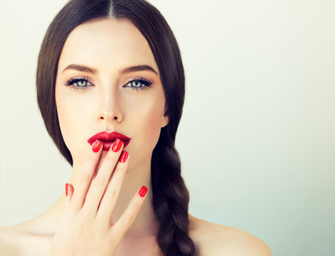 Beautiful brunette model girl with long braid hair . Hairstyle pigtail . Red lips and nails manicure . 