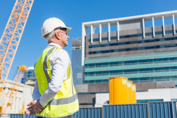 Senior foreman in glasses doing his job at building area on sunny day