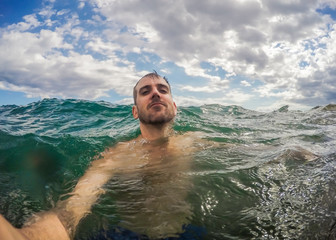 Man taking selfie while swimming off of a tropical island