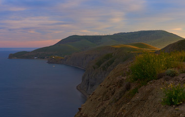 Scenic view of peaceful and calm green island with mountains and hills along coastline, ocean and clouds at sunrise. Panorama of amazing landscape by the sea with nobody around. Nature and environment