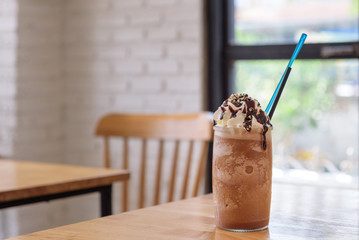 iced mocha with straw in tall glass on wooden table (coffee, ice, iced)