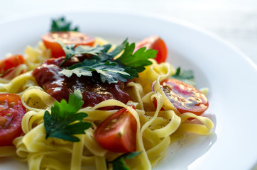 Tagliatelle pasta with tomato sauce decorated with basil leafs