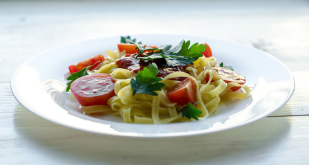 Tagliatelle pasta with tomato sauce decorated with basil leafs